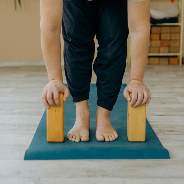 Person doing a stretching exercise on a mat in a bright studio with blue accents.